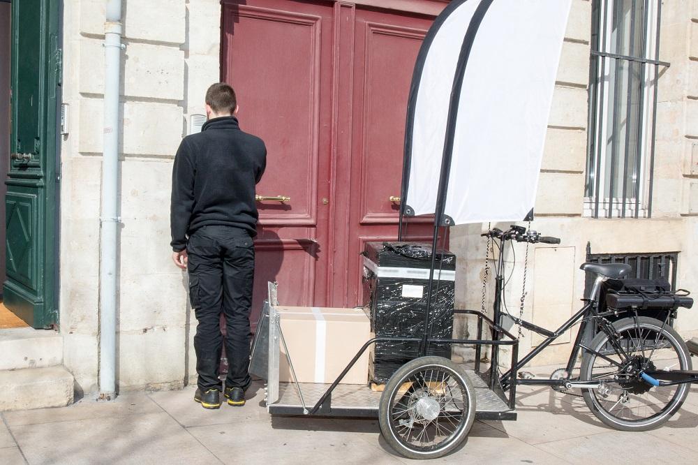 A person with a bicycle in front of a building Description automatically generated