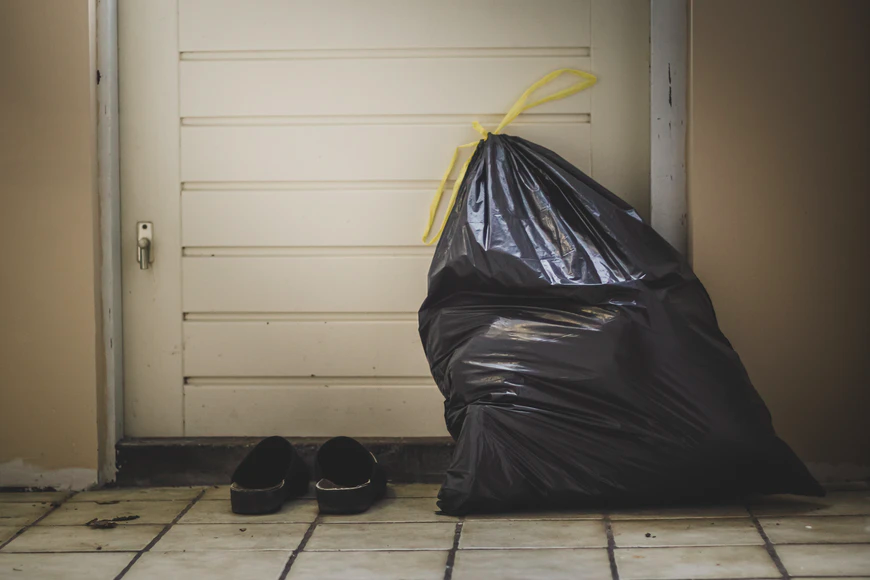 A trash bag lying outside a white door.