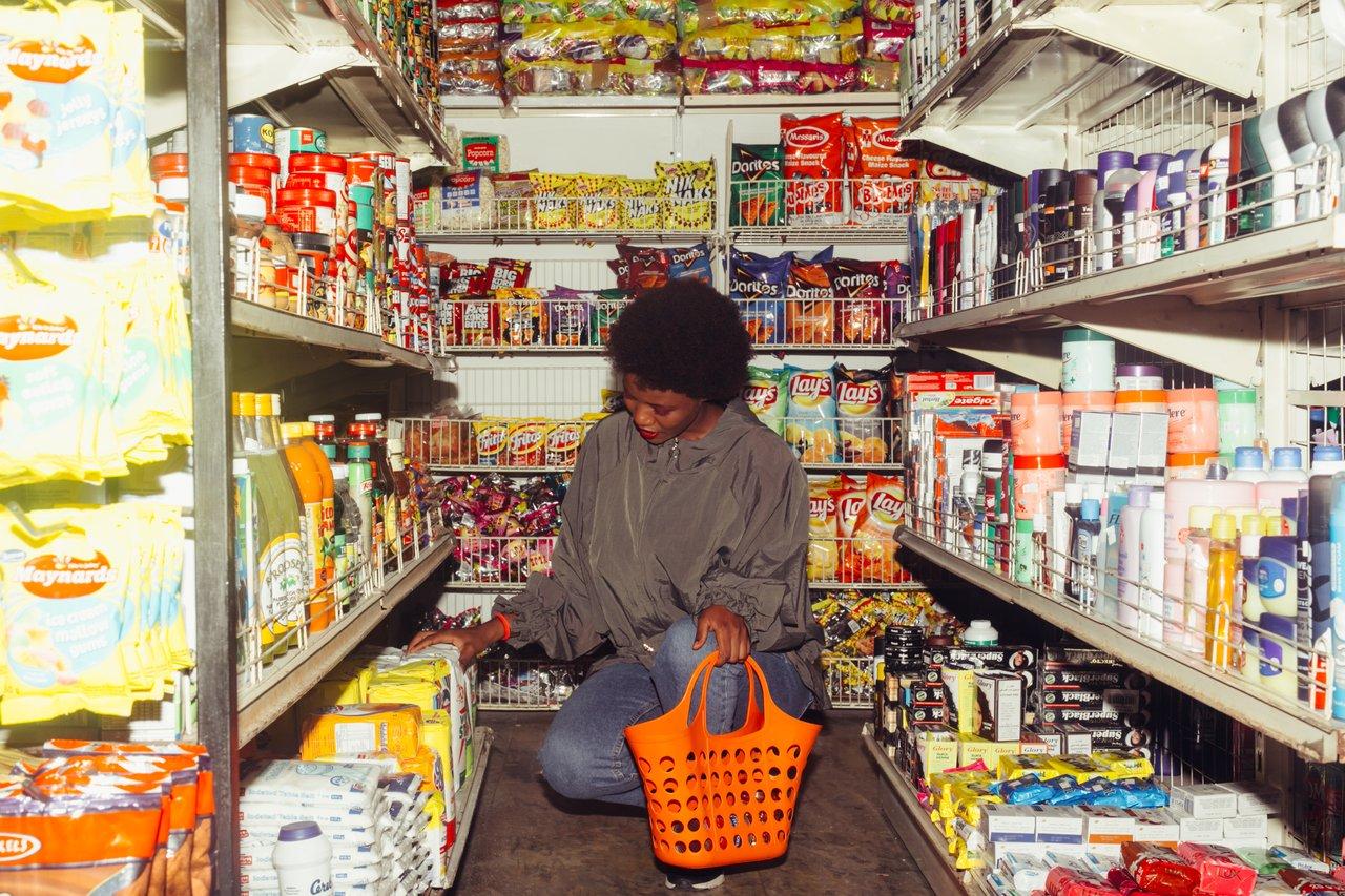 A woman crouching between to grocery store aisles.