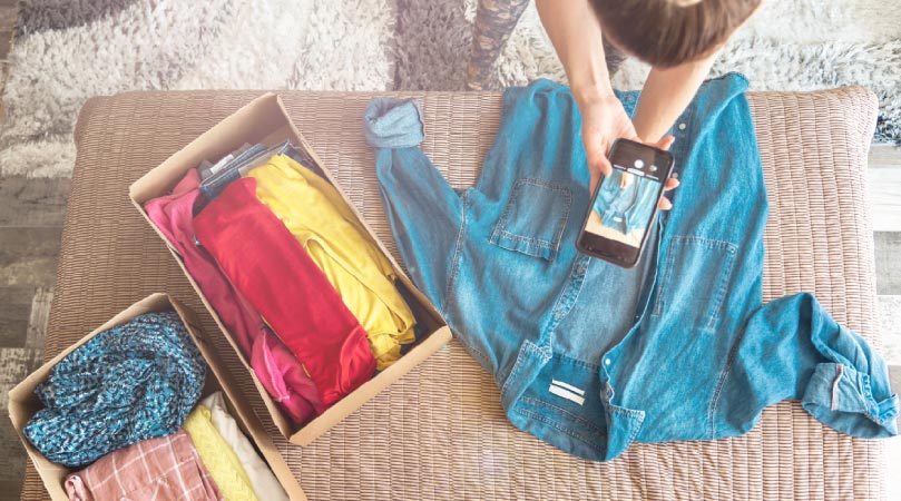 A woman taking pictures of her old clothes to sell online