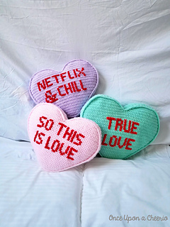 three candy heart pillows in different colors