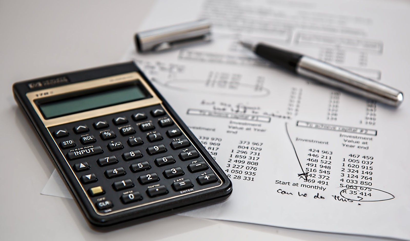 Calculator with written papers and ballpen.