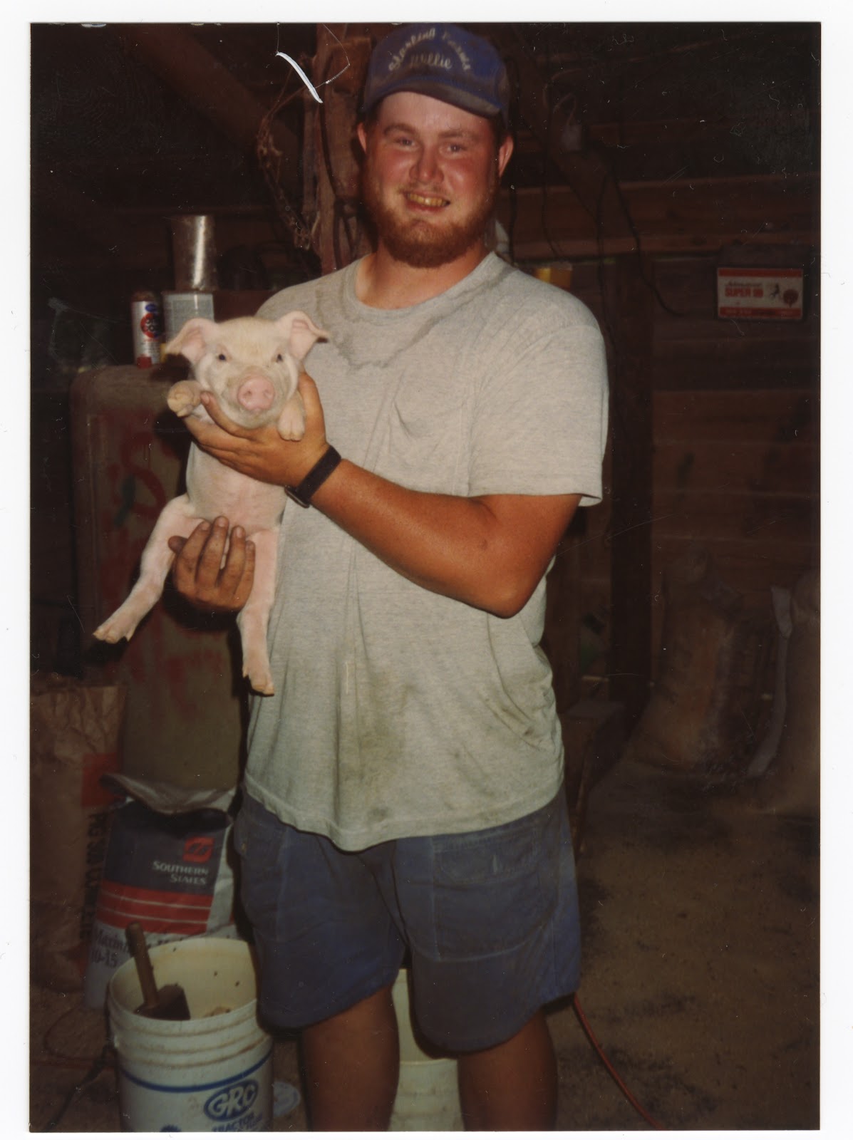 farmer smiling and holding a pig. 