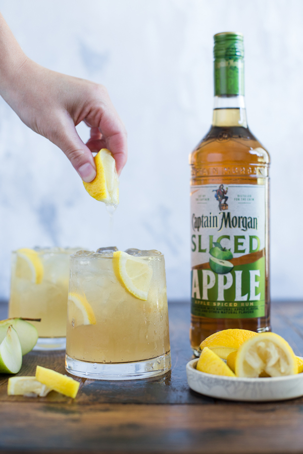 Hand that makes a cocktail and adding lemon