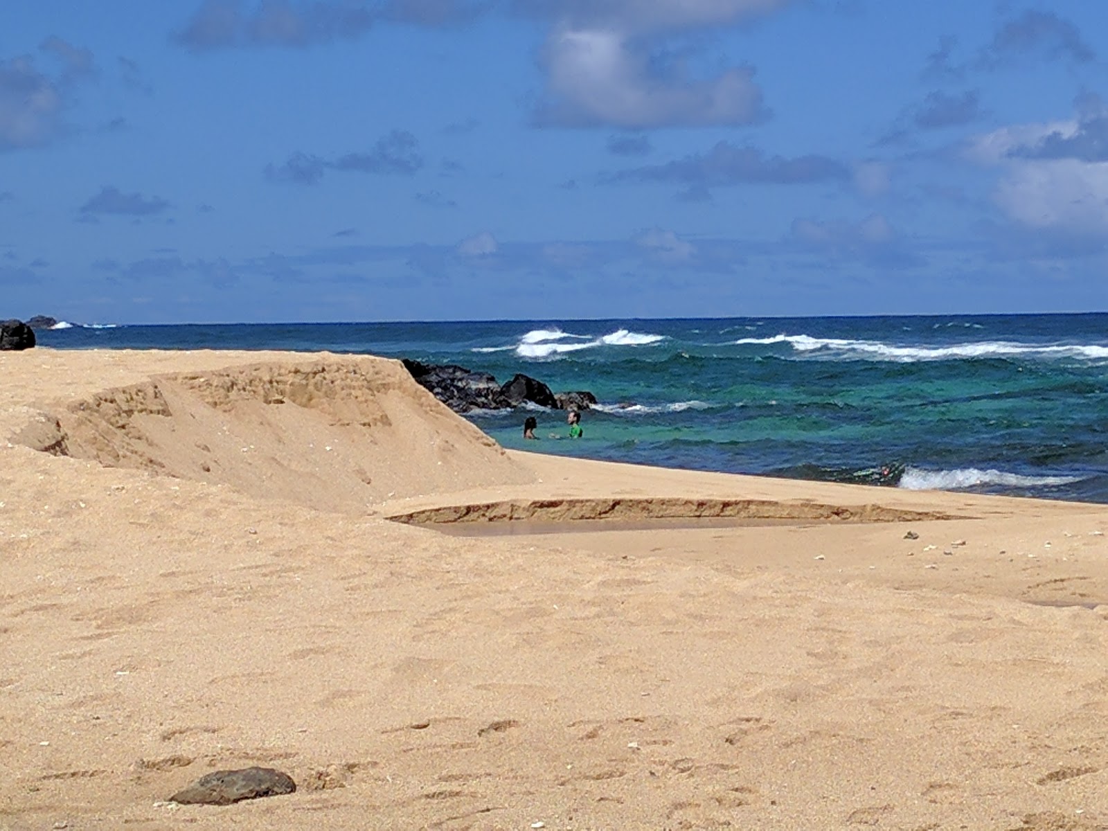 Foto van Kaluakai Beach met helder zand & rotsen oppervlakte