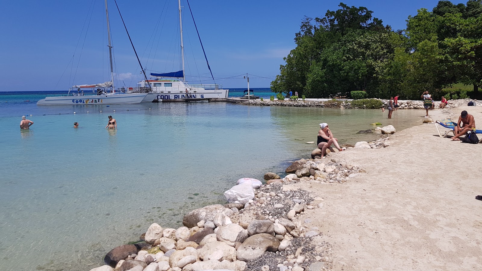 Foto van Mahogany Beach met helder zand & rotsen oppervlakte