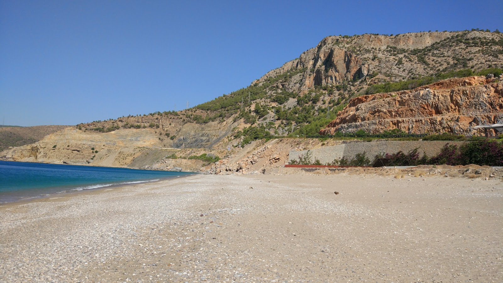 Foto af Yanisli Cave beach bakket op af klipperne