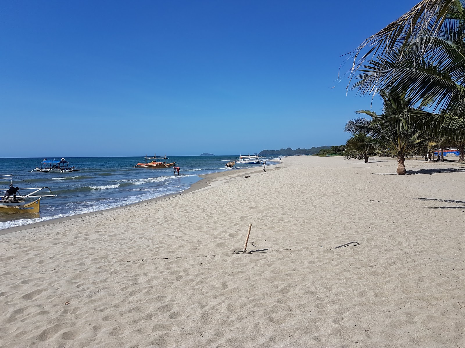 Valokuva Poblacion Beachista. pinnalla kirkas hiekka:n kanssa