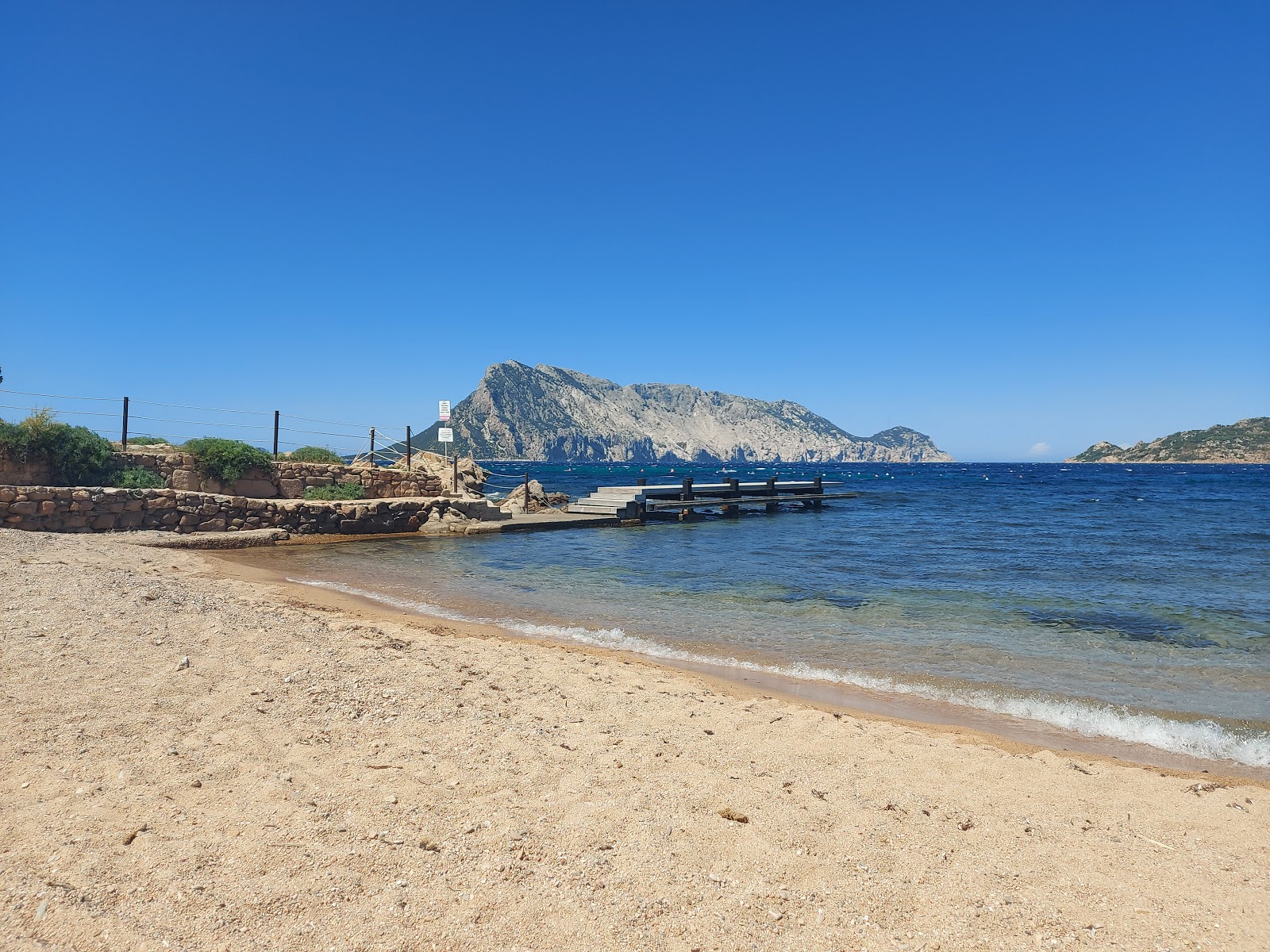 Foto von Spiaggia di Cala Ginepro
 mit beiger sand Oberfläche