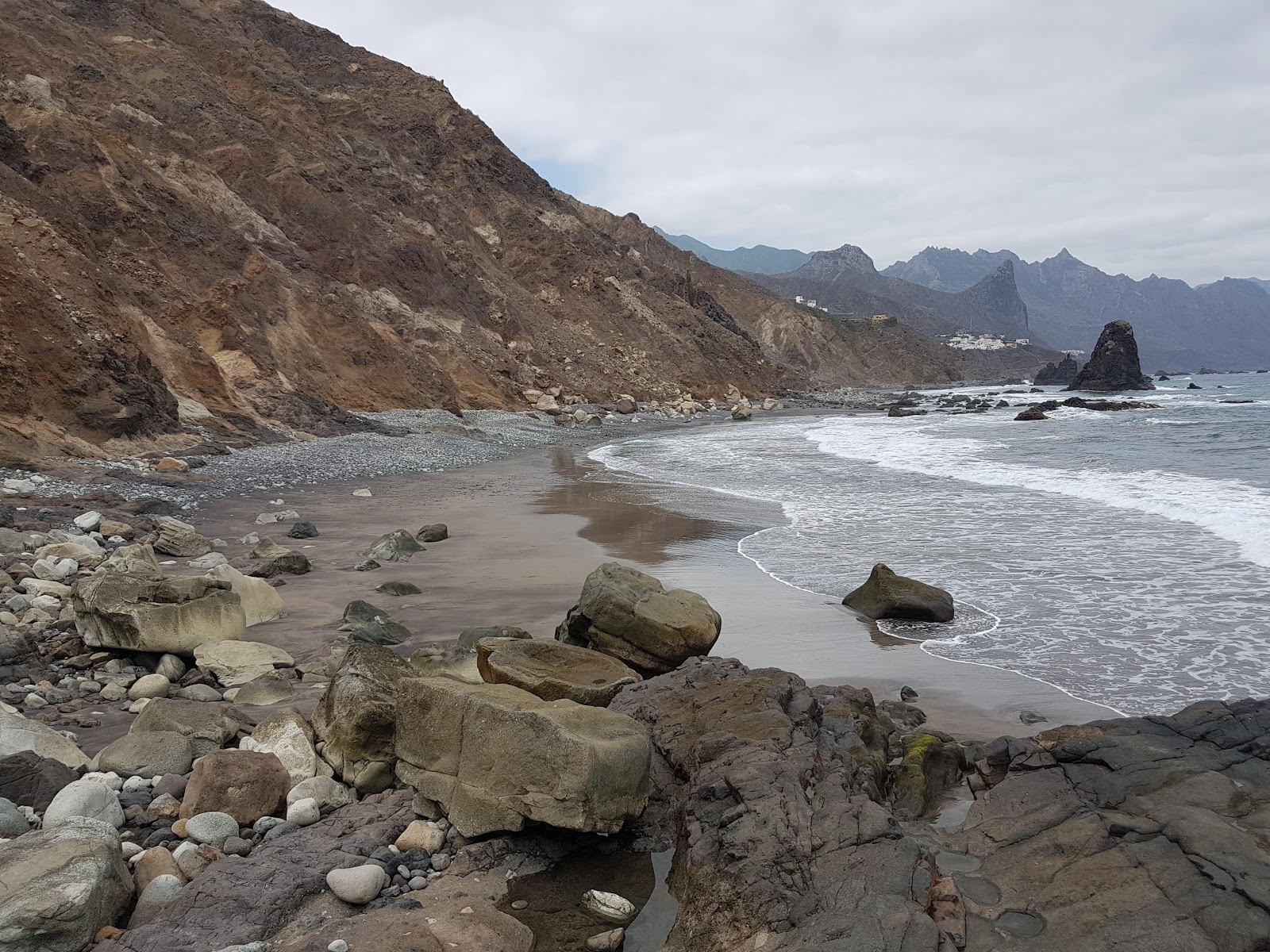 Foto av Playa Fabian med harmaa hiekka ja kivi yta