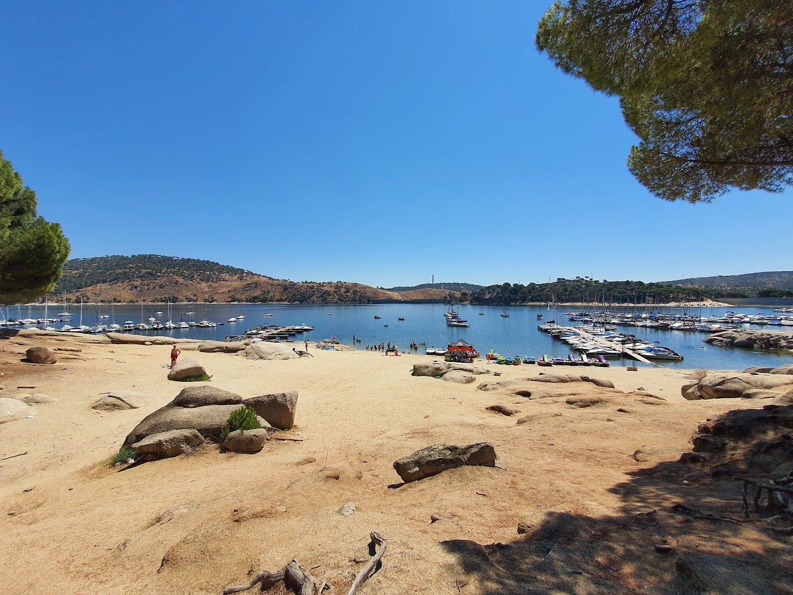 Foto di Zona de bano del embalse con una superficie del sabbia beige