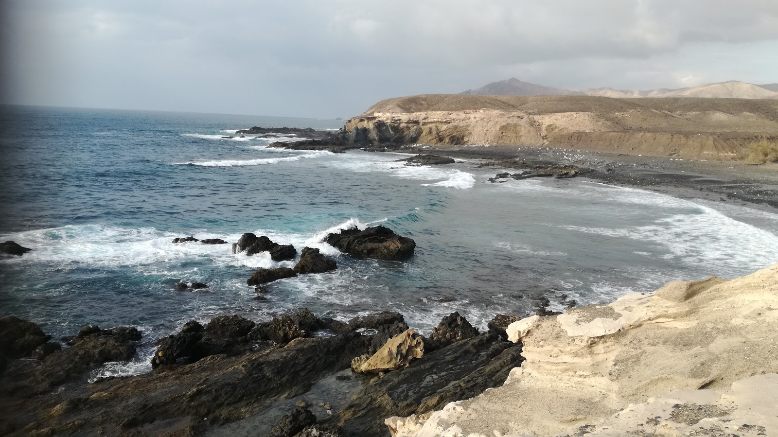Foto av Playa de Ugan omgiven av berg