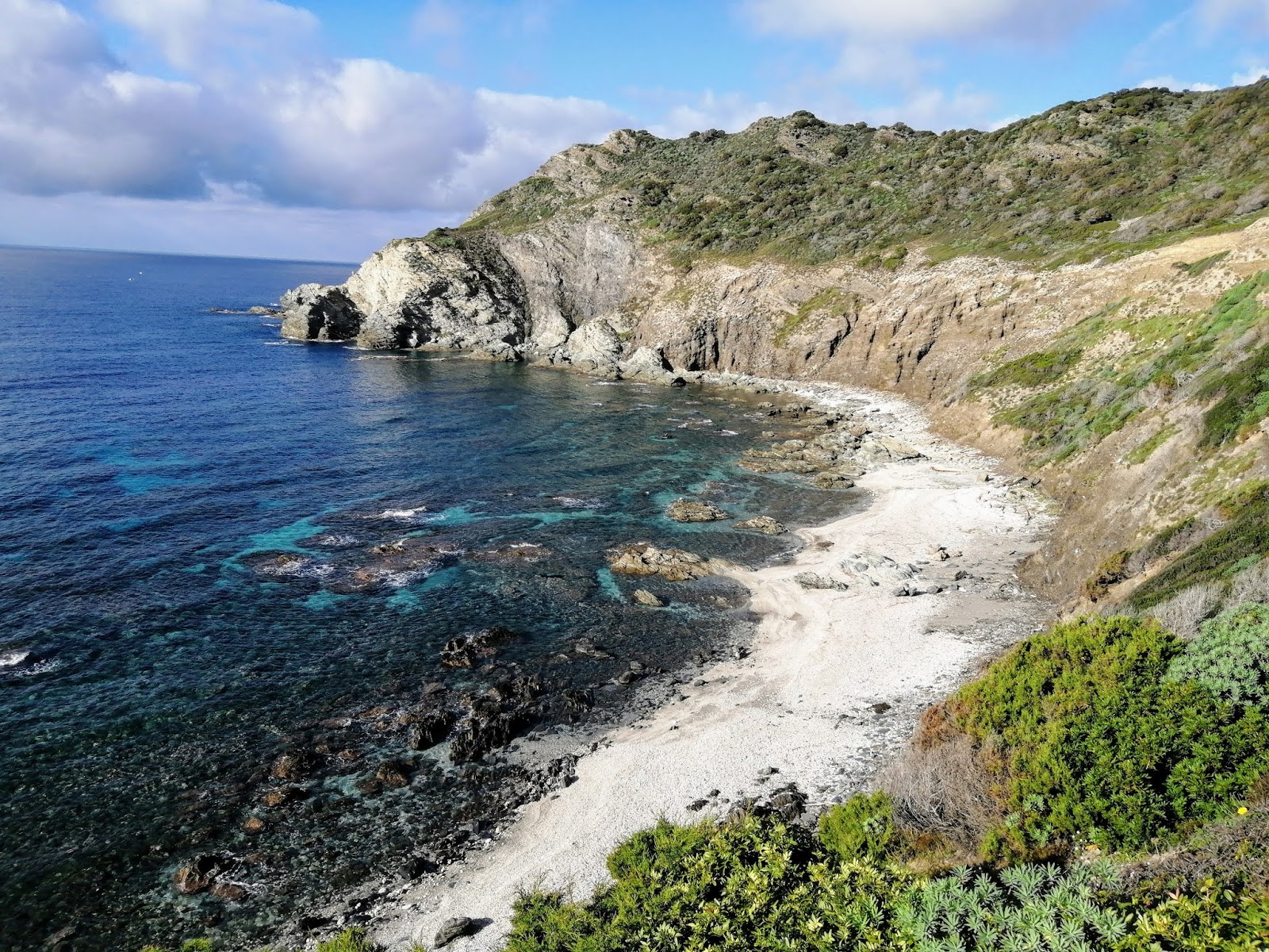 Foto di Cala di Punta Agliastroni con una superficie del sabbia luminosa e rocce