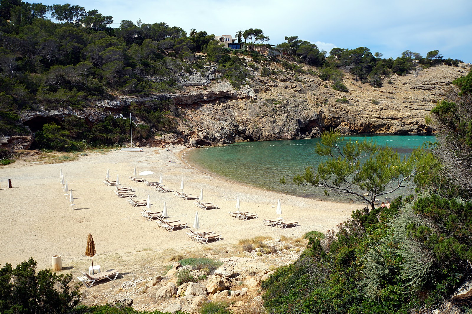 Foto av Cala Moli med harmaa hiekka ja kivi yta