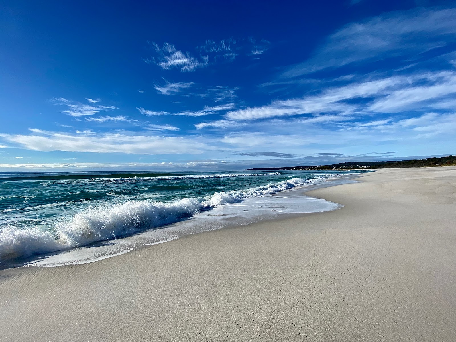 Valokuva Jeanneret Beachista. pinnalla sininen puhdas vesi:n kanssa