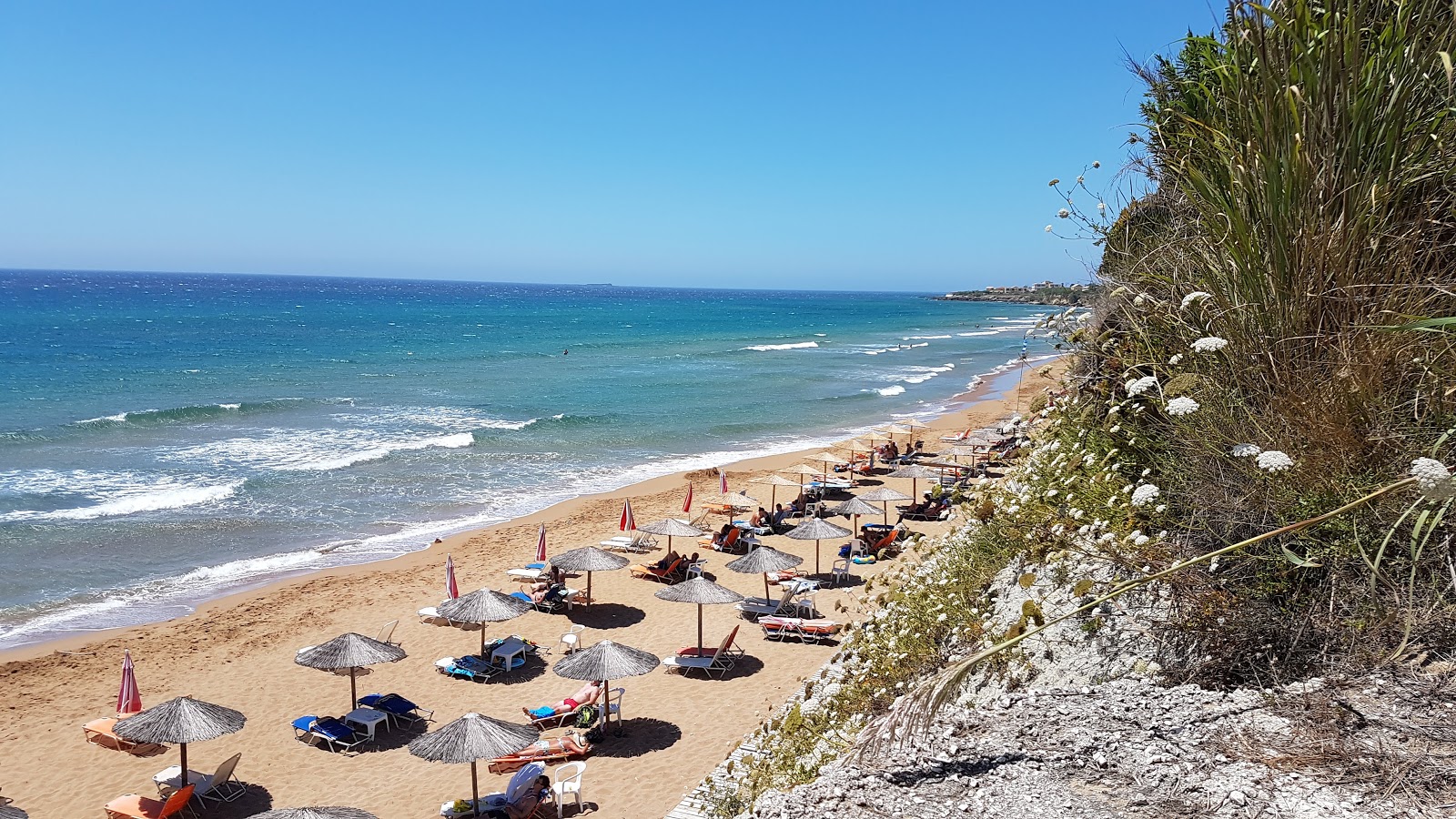 Photo de Agios Georgios beach avec sable fin brun de surface