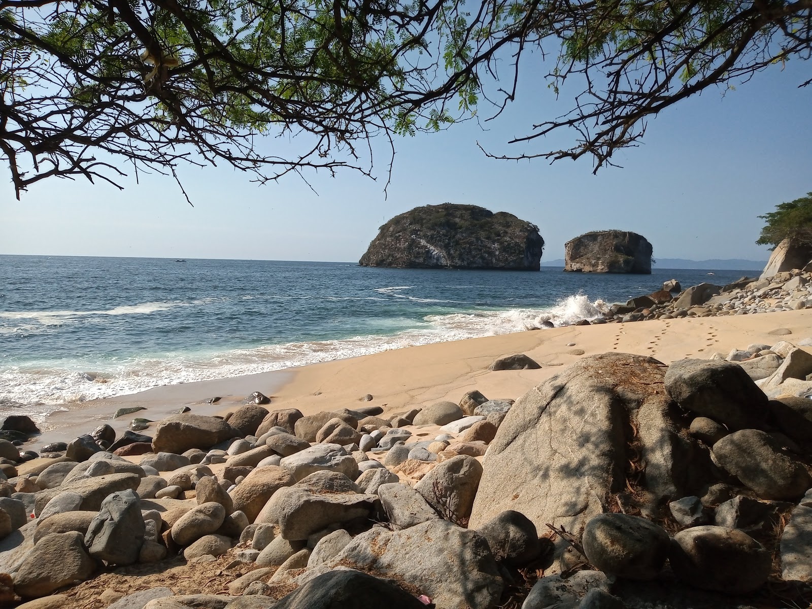 Valokuva Arcos beachista. pinnalla kirkas hiekka ja kivet:n kanssa