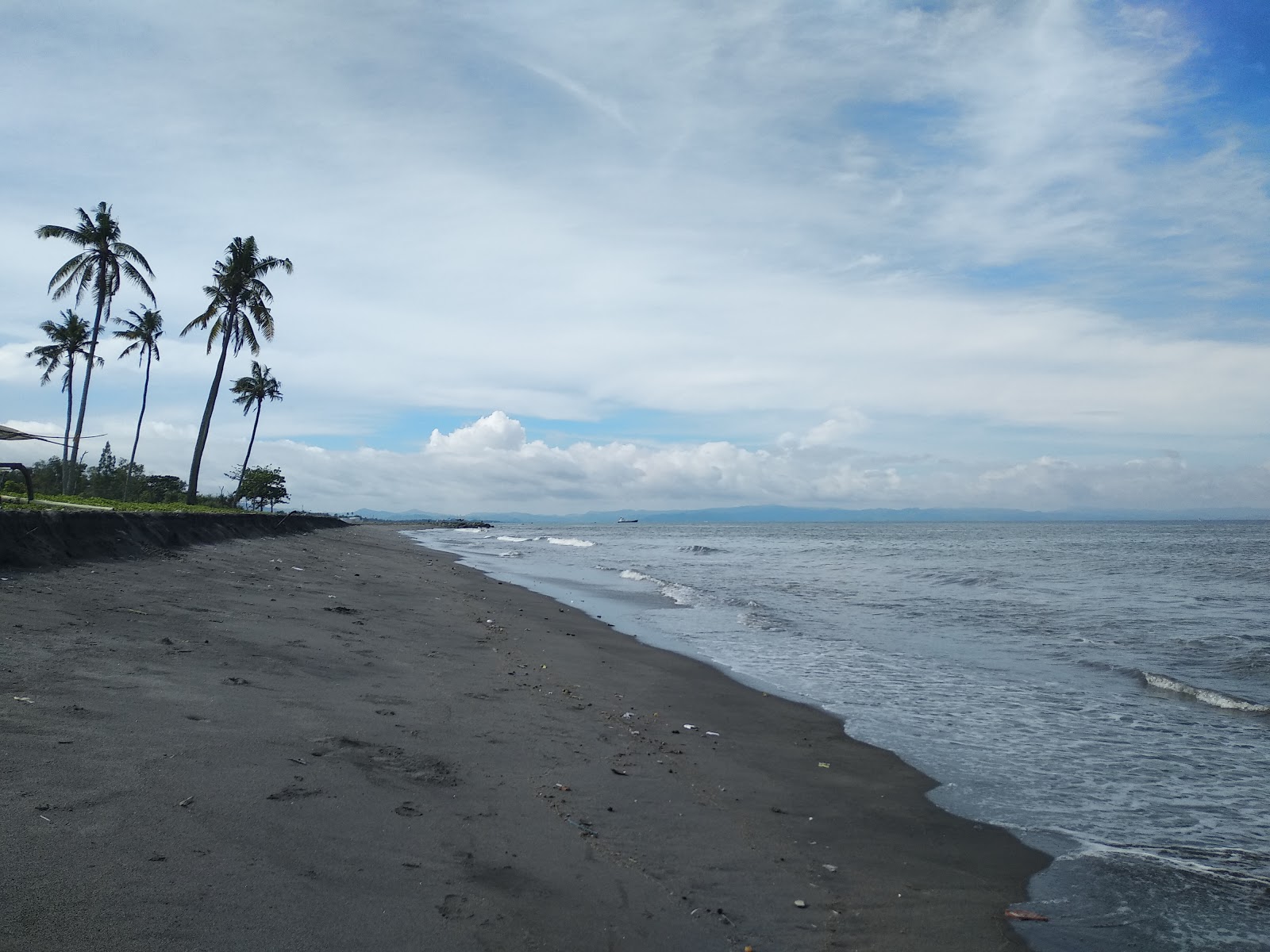 Foto di Penghulu Agung Beach con una superficie del sabbia scura