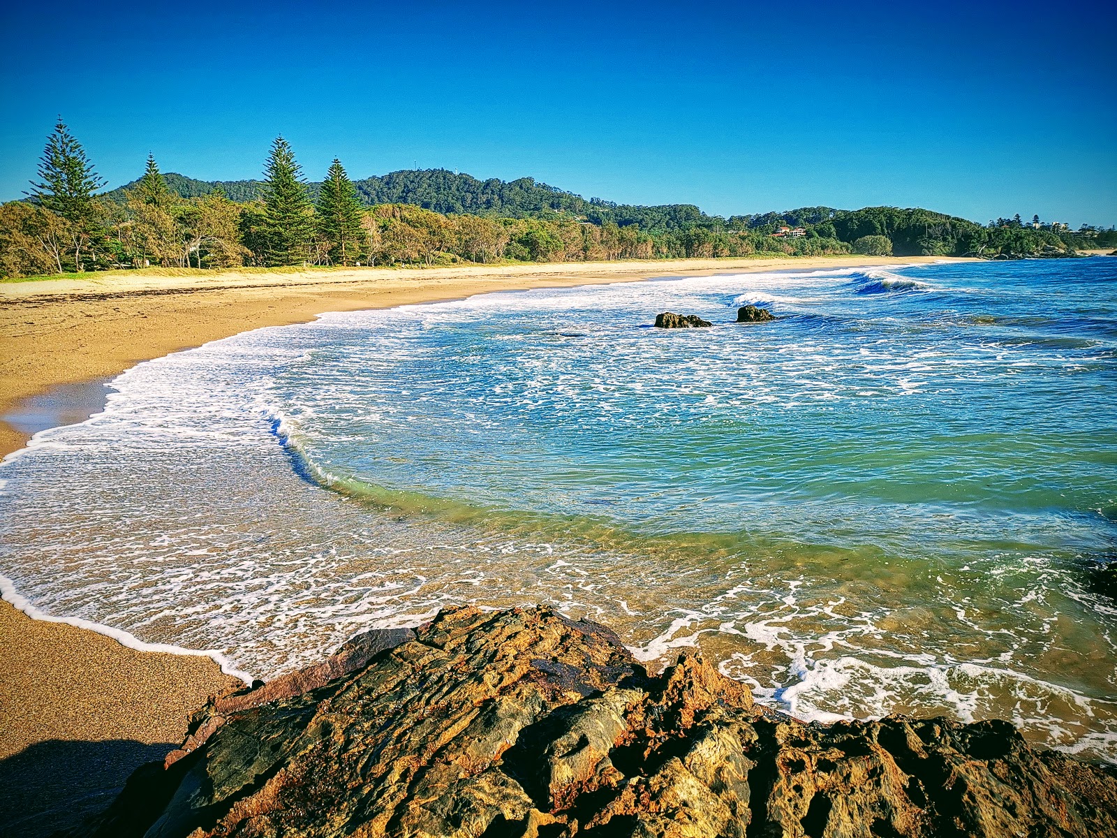 Foto von Charlesworth Bay Beach umgeben von Bergen