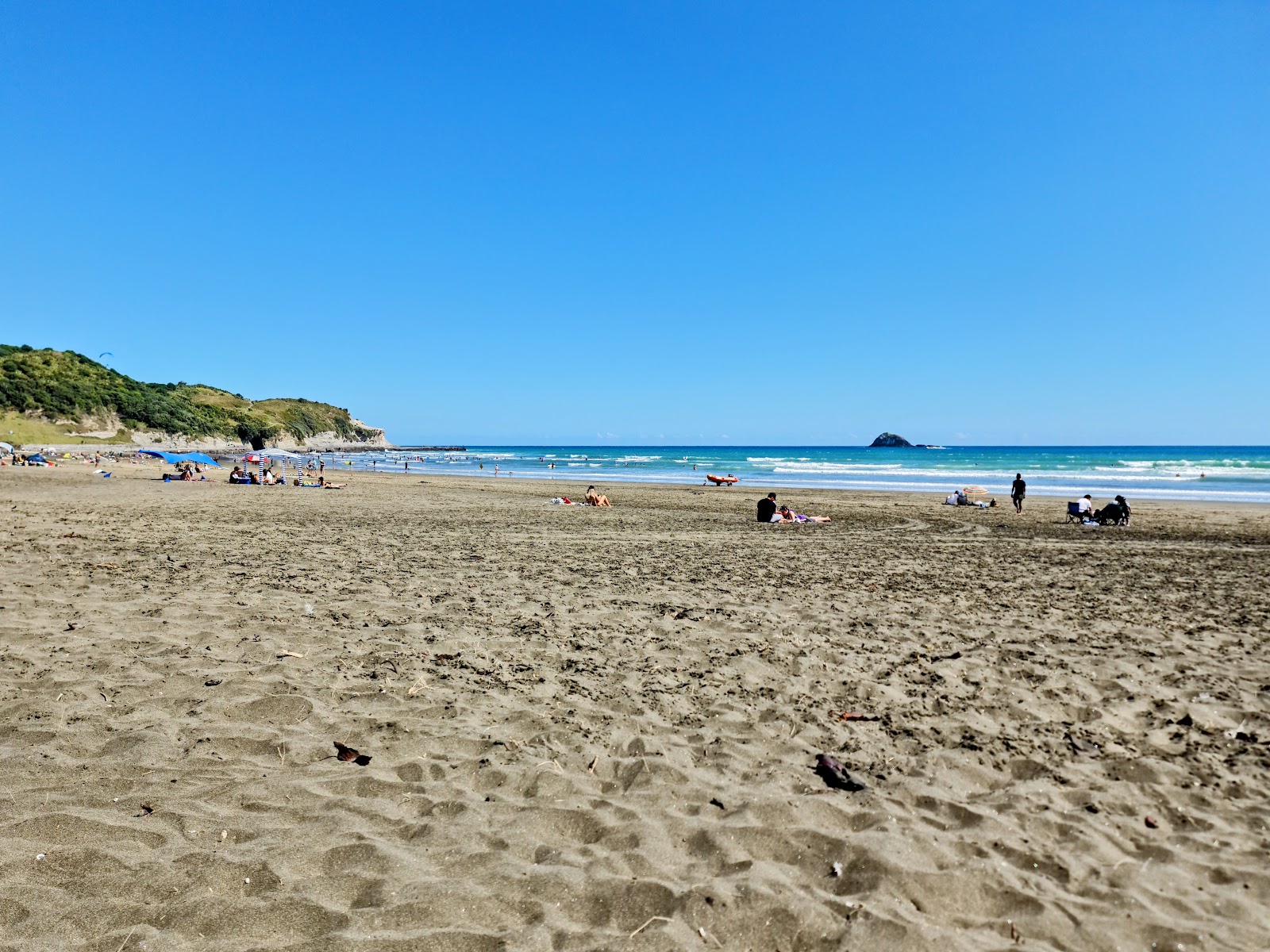 Valokuva Muriwai Beachista. pinnalla beige iekka:n kanssa
