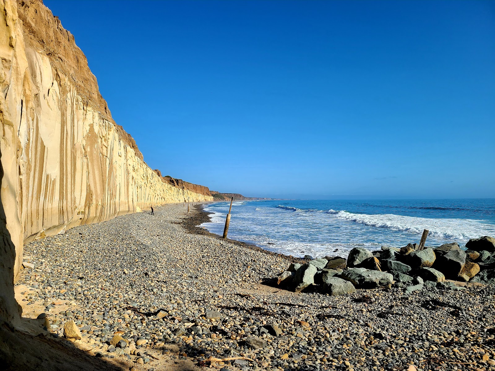 Valokuva Trails beachista. pinnalla kevyt hiekka ja kivi:n kanssa