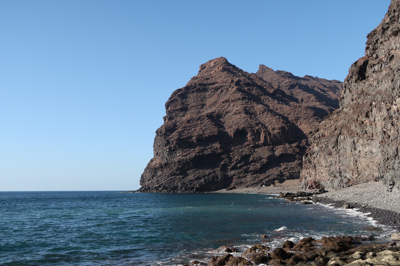 Foto van Playa de Tasartico met zand met stenen oppervlakte