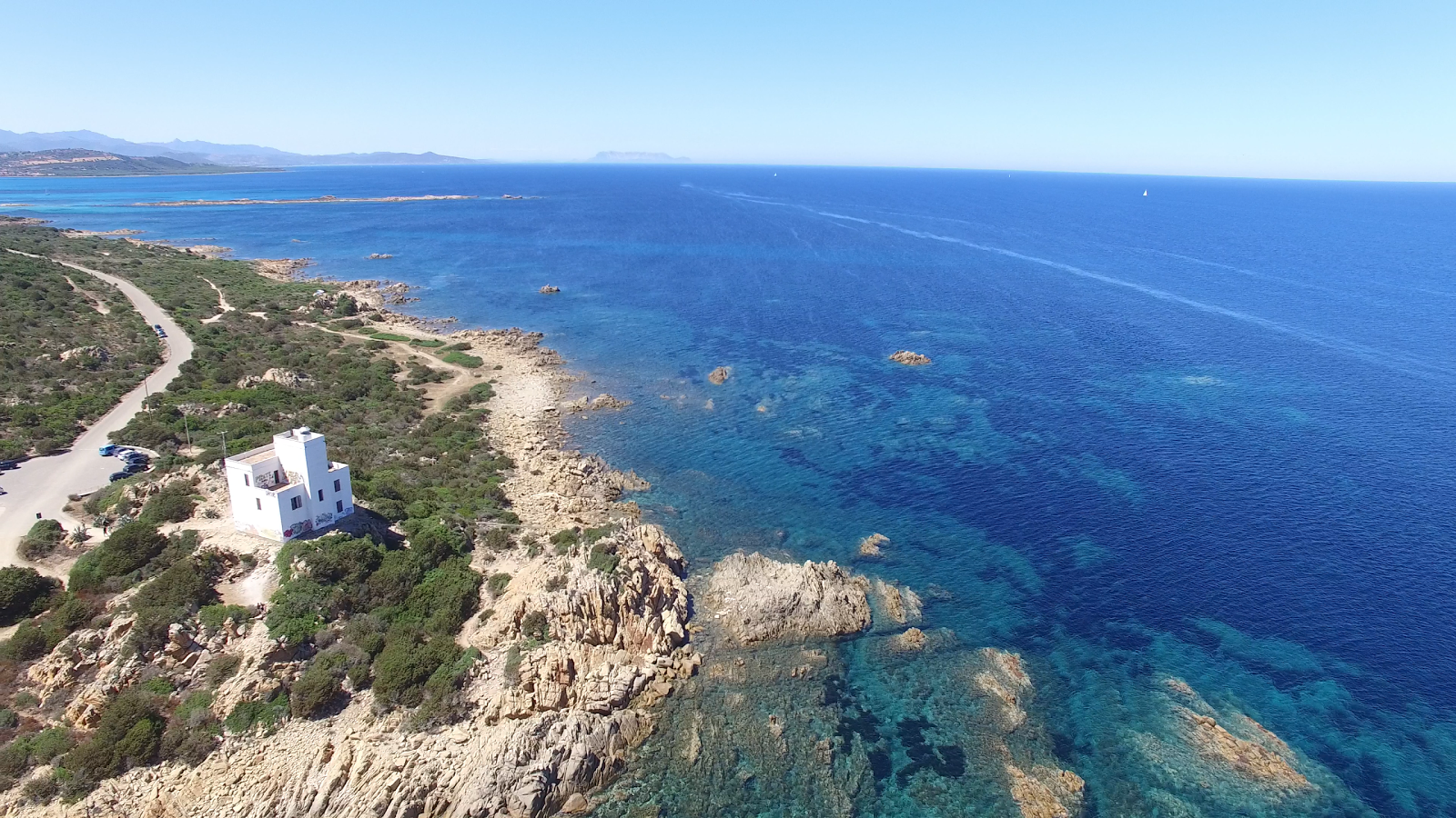 Faro di Capo Comino的照片 带有岩石覆盖表面