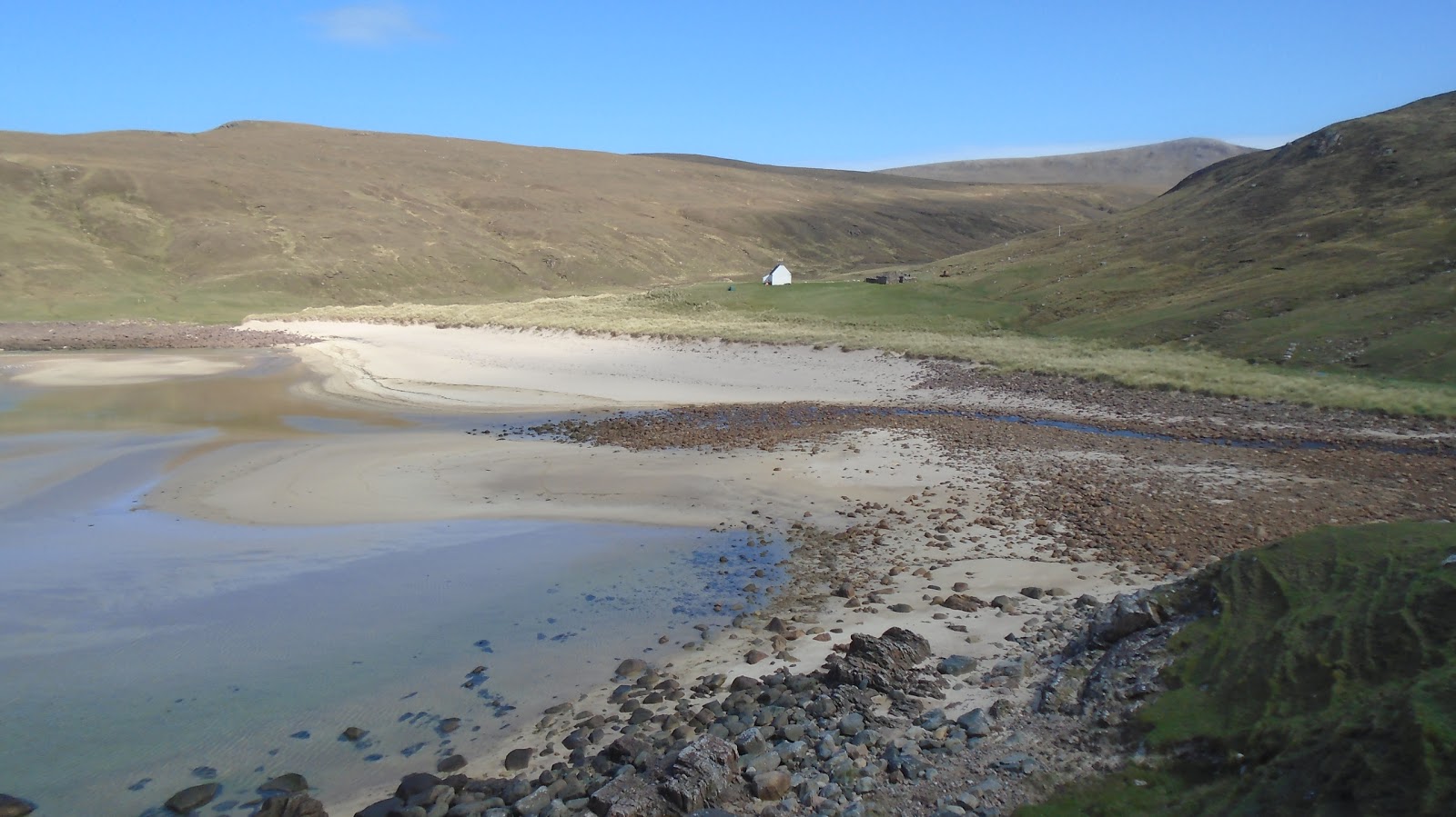 Foto av Kearvaig Bothy med turkos rent vatten yta