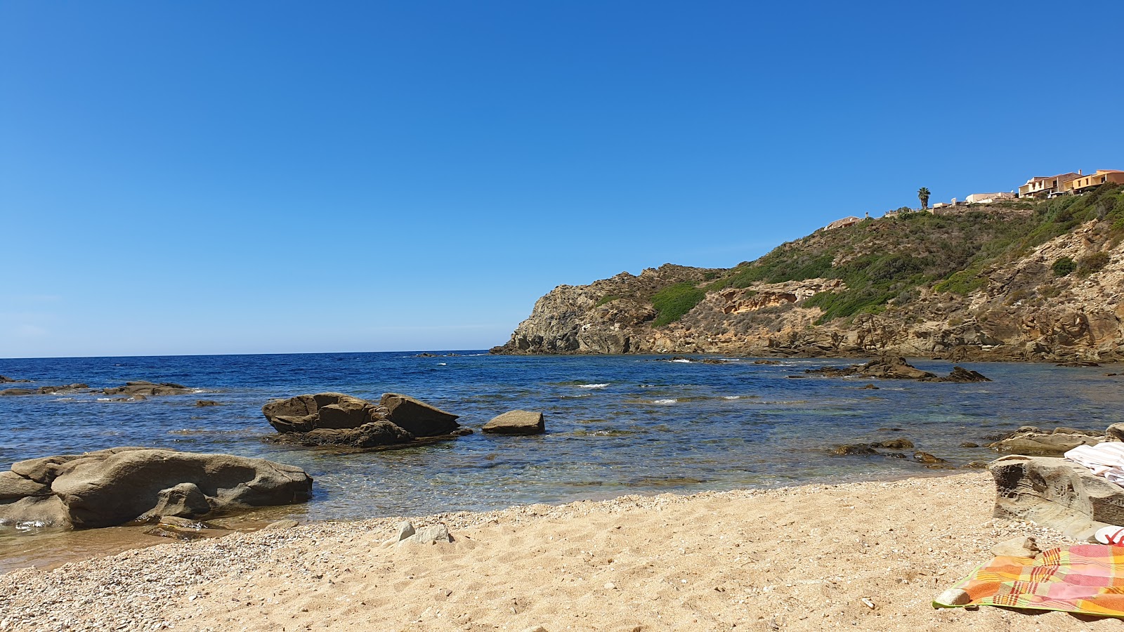 Foto von Cala Is Cannisonis Beach mit beiger sand & steine Oberfläche