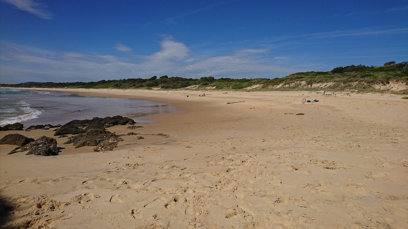 Foto de Woolgoolga Back Beach com areia fina e brilhante superfície