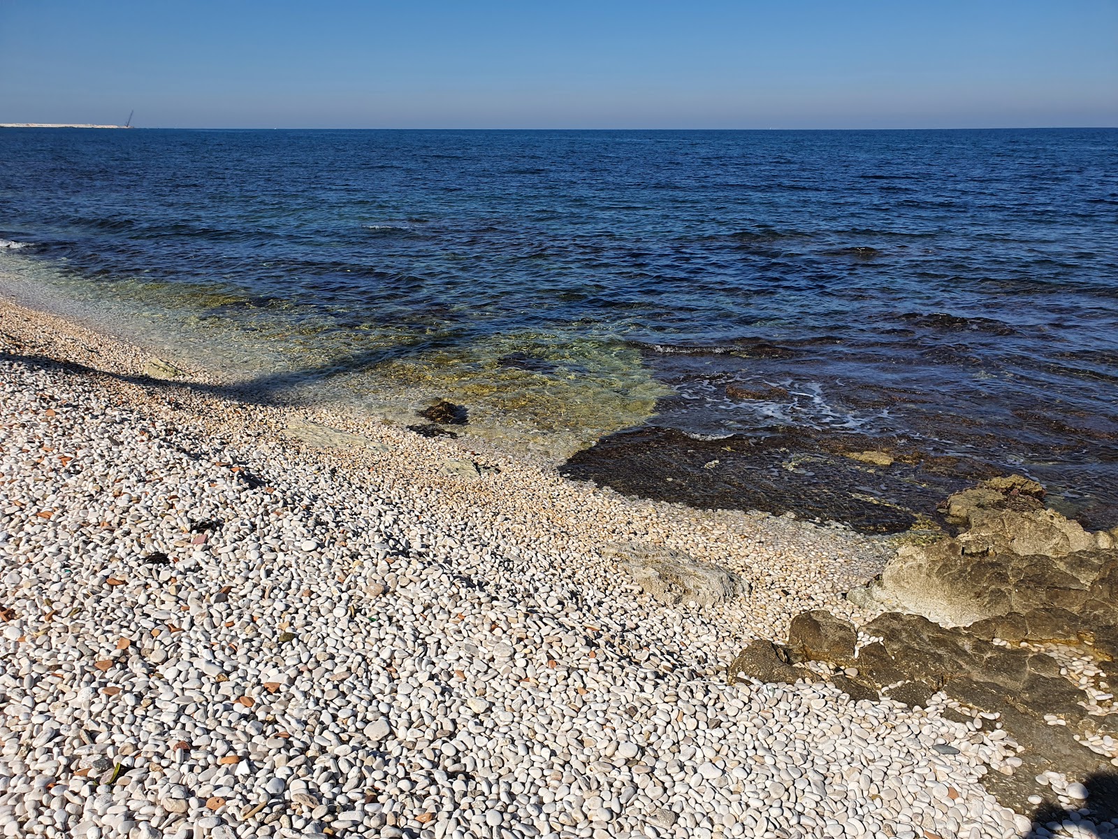 Valokuva First Cala beachista. pinnalla sininen puhdas vesi:n kanssa