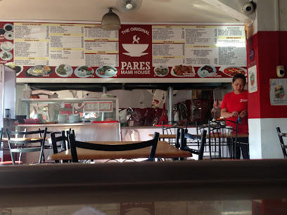Interior of a restaurant with a menu board and a staff member in a red shirt arranging tables.