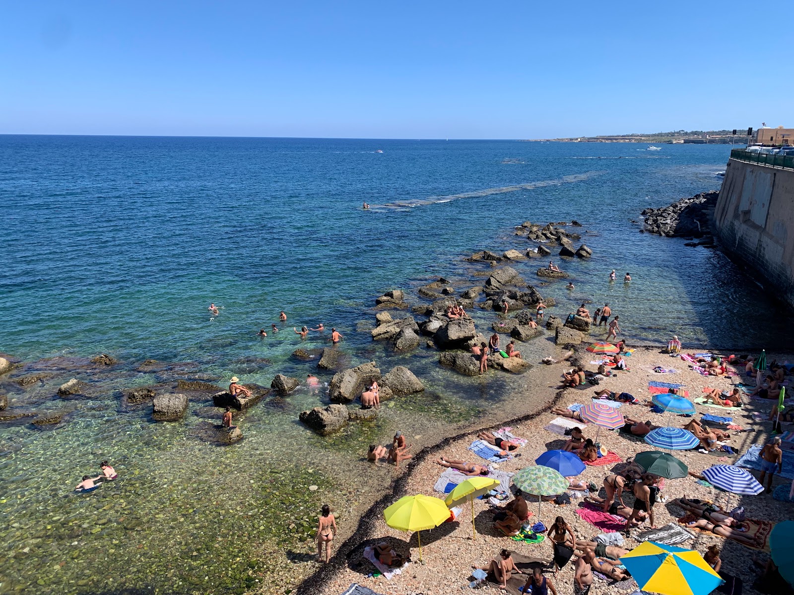 Cala Rossa Beach的照片 带有灰色沙和岩石表面