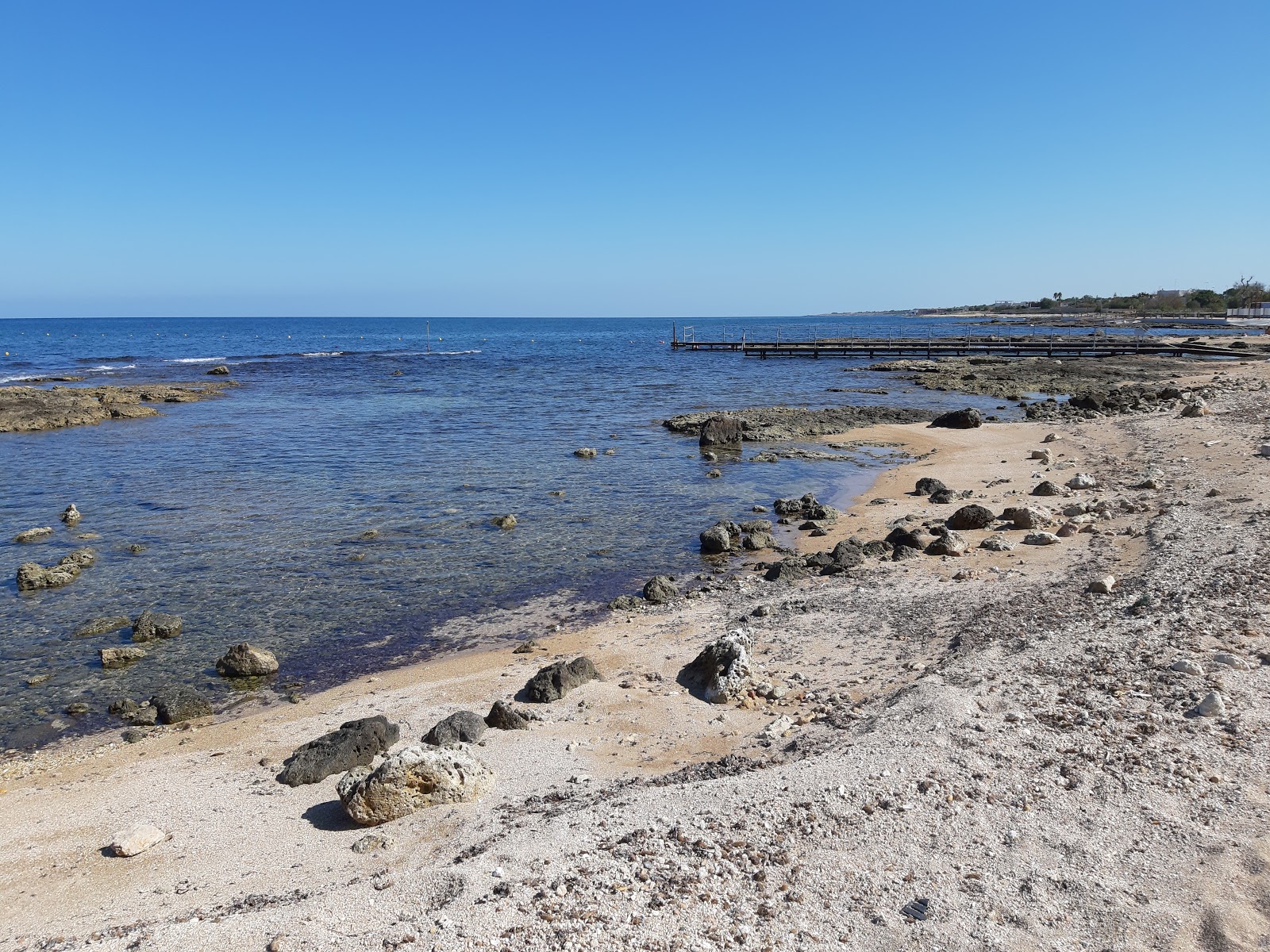 Foto de Fischietto Beach com areia bege e rochas superfície