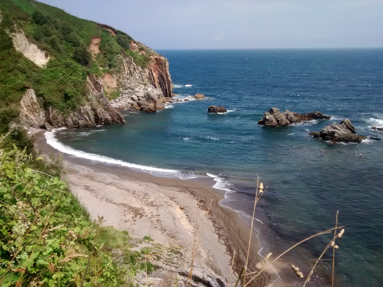 Foto von Playa de Pendueles mit grauer sand & felsen Oberfläche