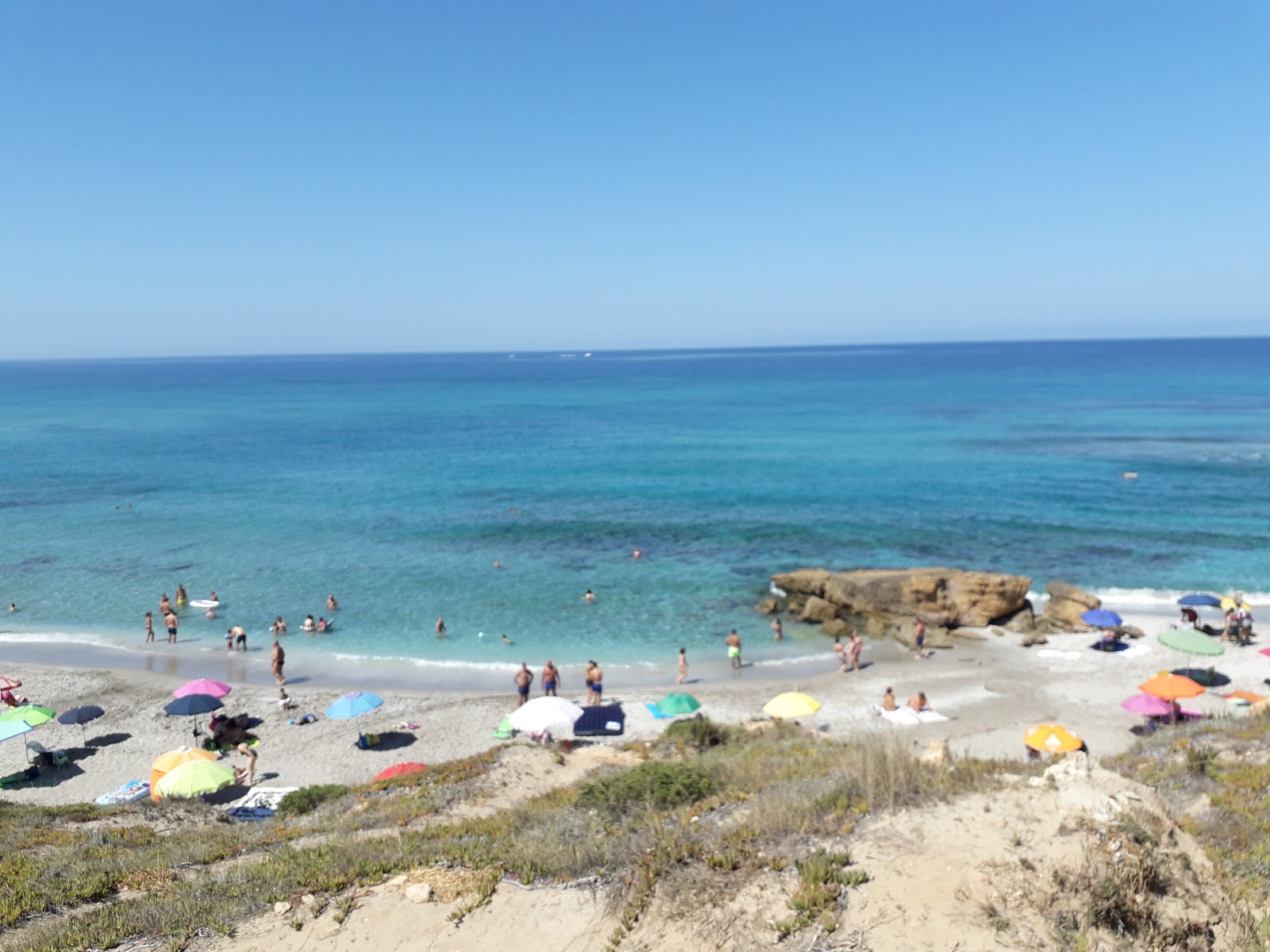 Valokuva Spiaggia di Mare Mortoista. pinnalla sininen puhdas vesi:n kanssa