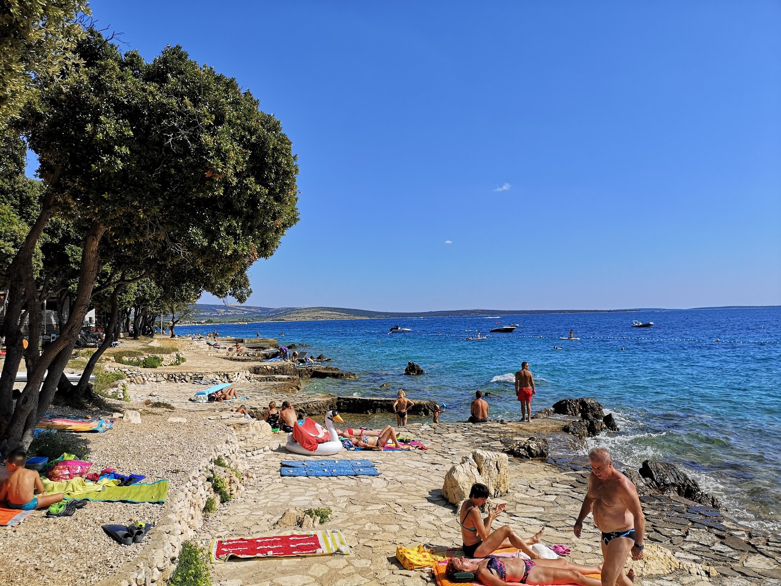 Foto av Scare beach med små beige småsten yta