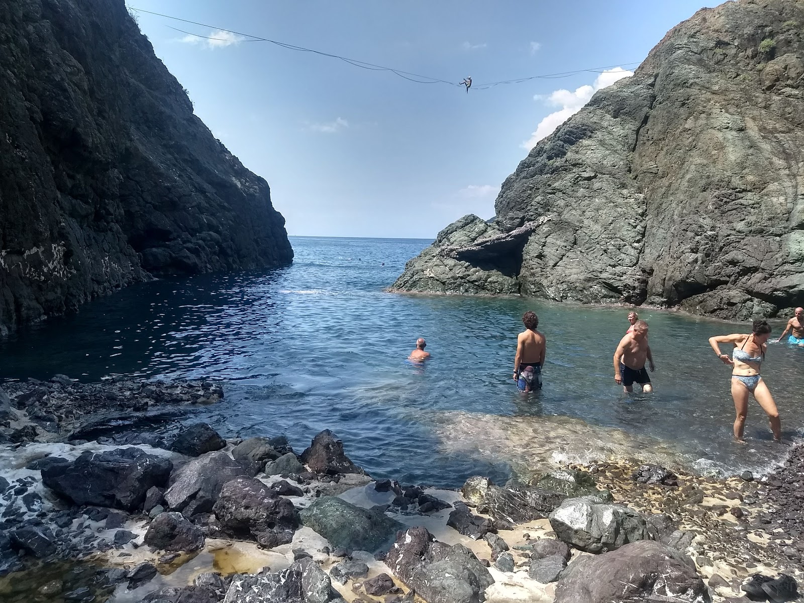 Valokuva Spiaggia di Porto Pidocchioista. tukeutunut kallioilla