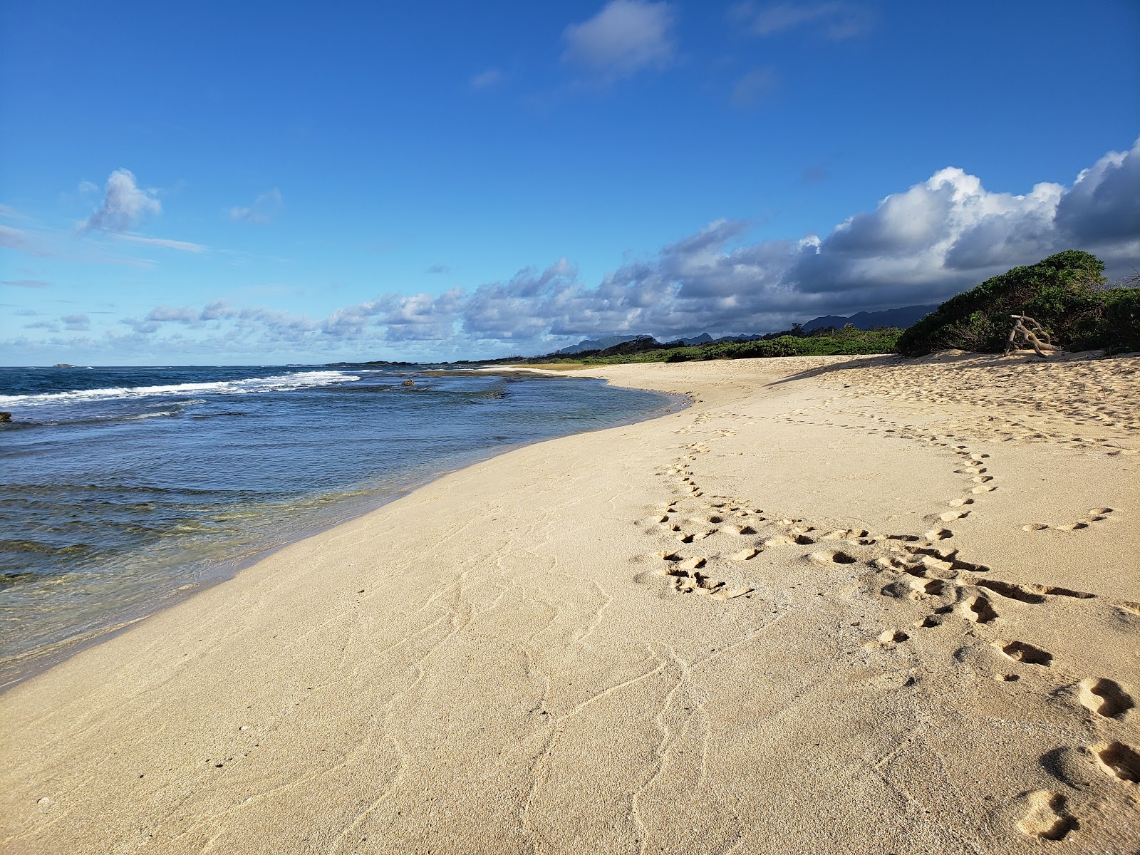 Valokuva Kahuku Beachista. pinnalla kirkas hiekka ja kivet:n kanssa