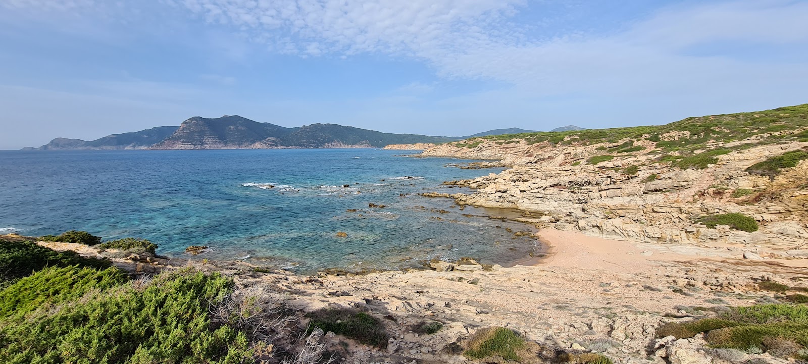 Fotografija Spiaggetta a nord di Cala del Turco z svetel pesek in kamni površino