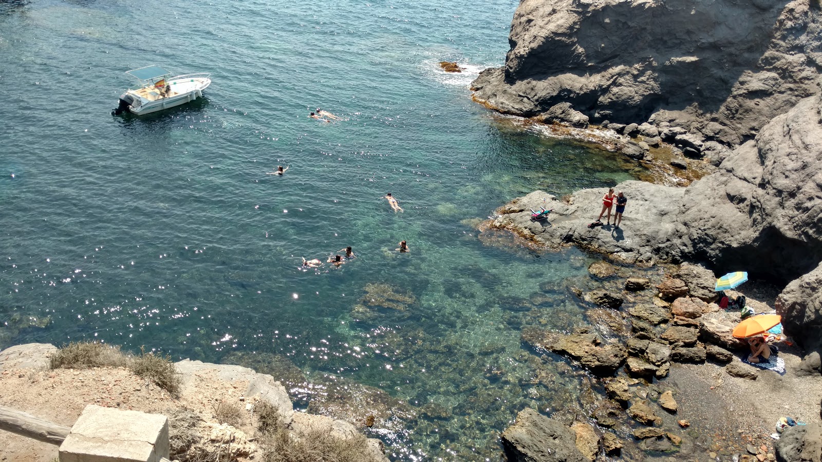 Fotografija Cala de las Melvas z musta hiekka ja kivi površino