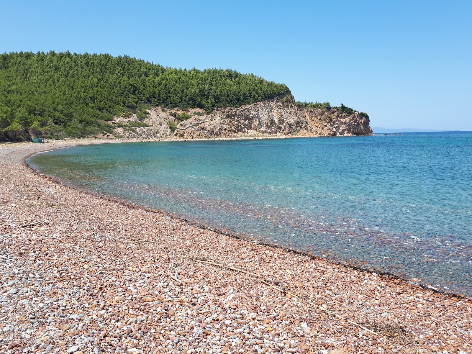 Foto av Mourtias beach med musta hiekka ja kivi yta