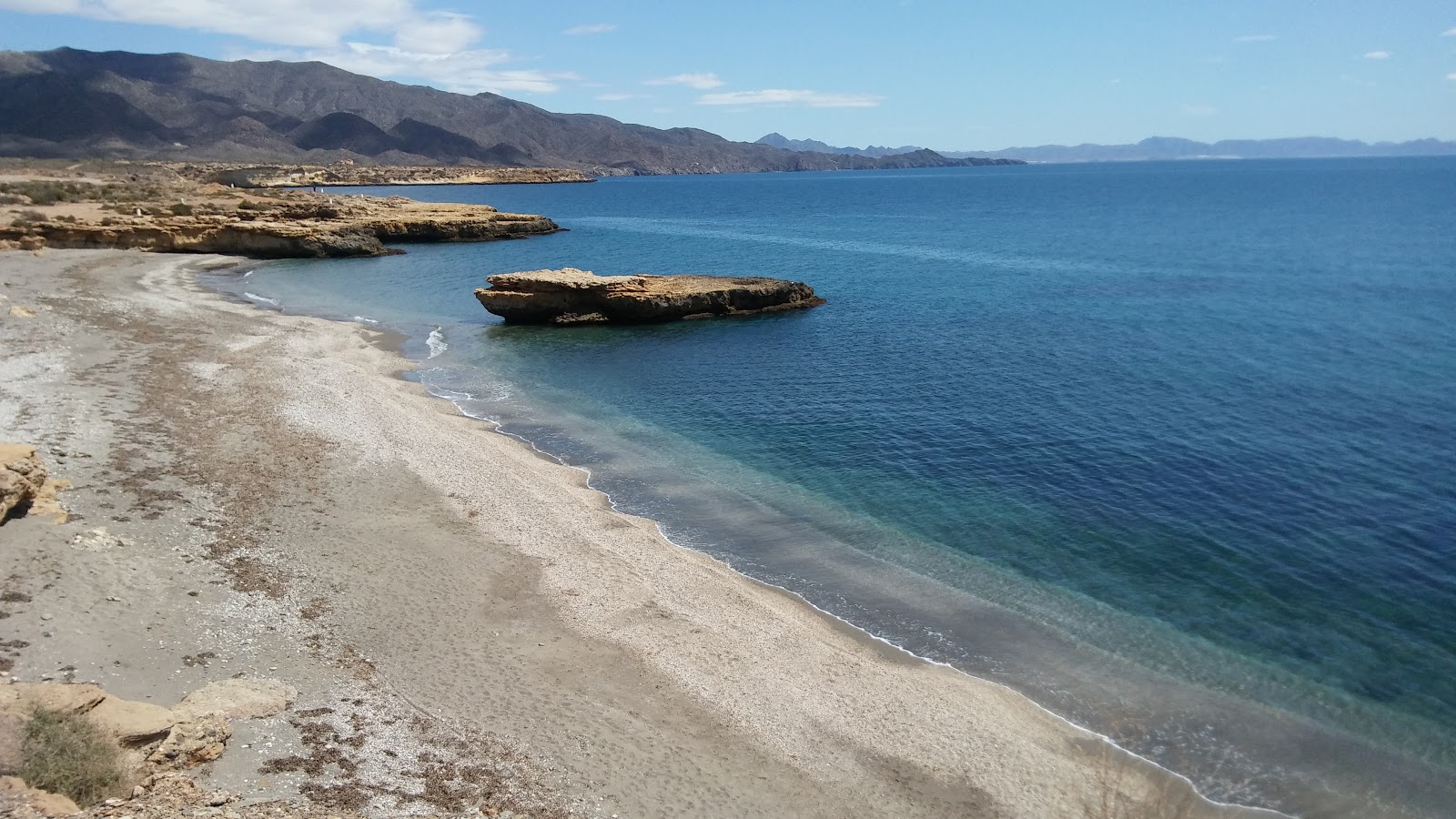 Foto di Playa de la Galera con una superficie del sabbia di conchiglie grigia