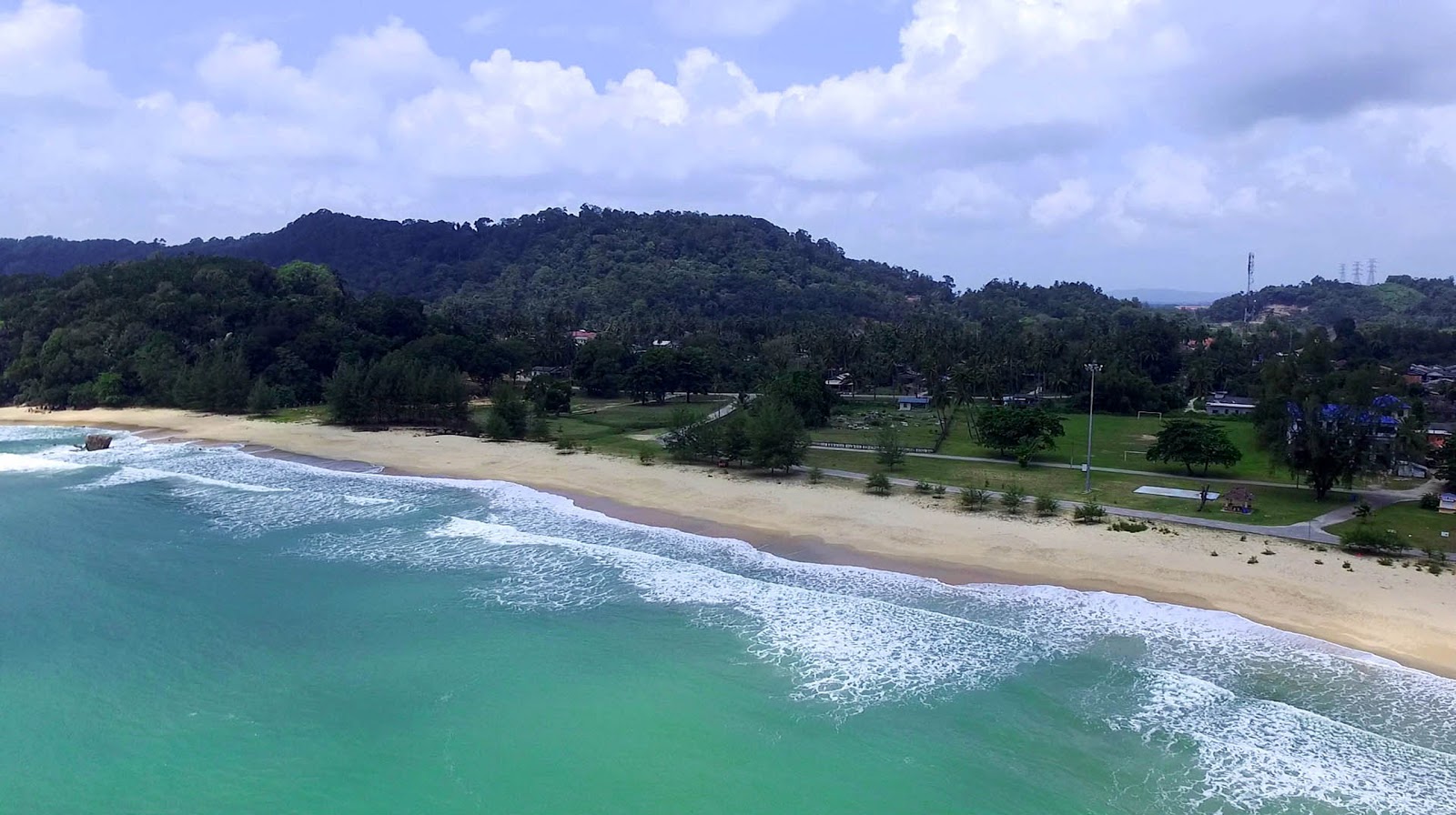 Foto av Teluk Kalong Beach omgiven av klippor