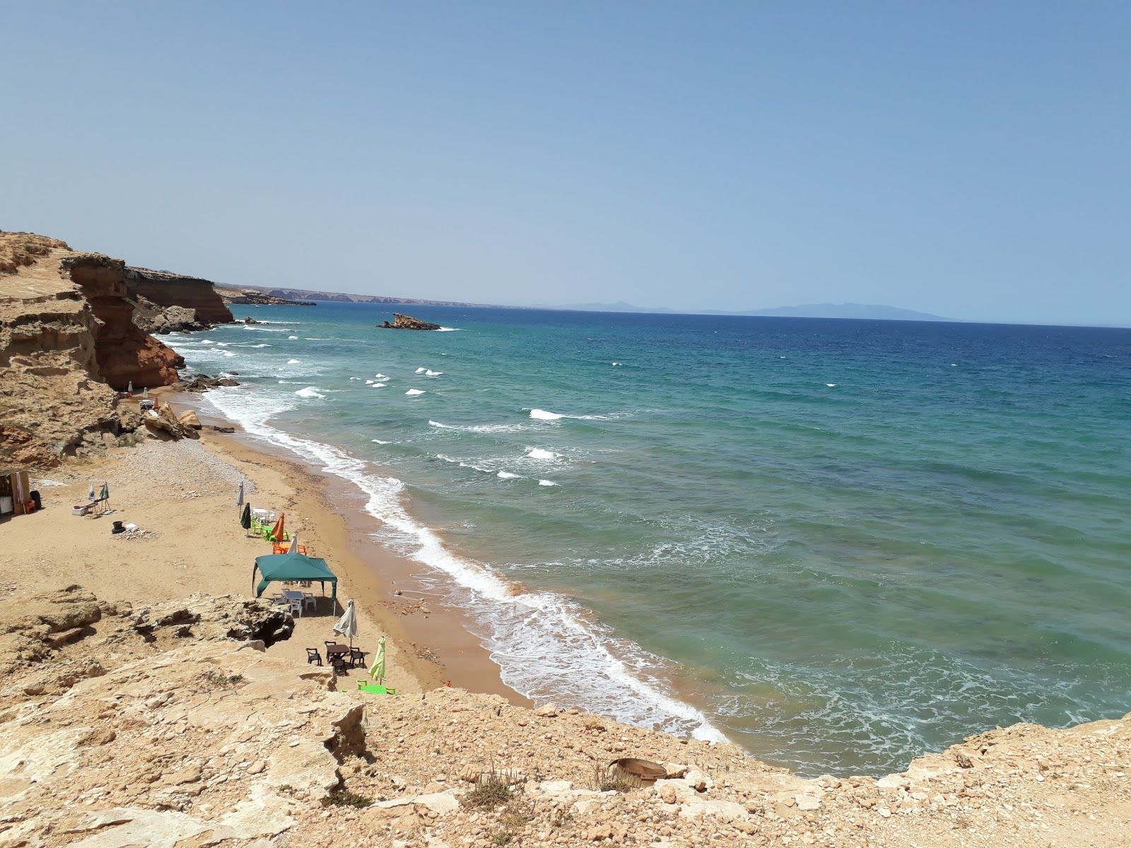 Φωτογραφία του Red beach με καφέ άμμο και βράχια επιφάνεια