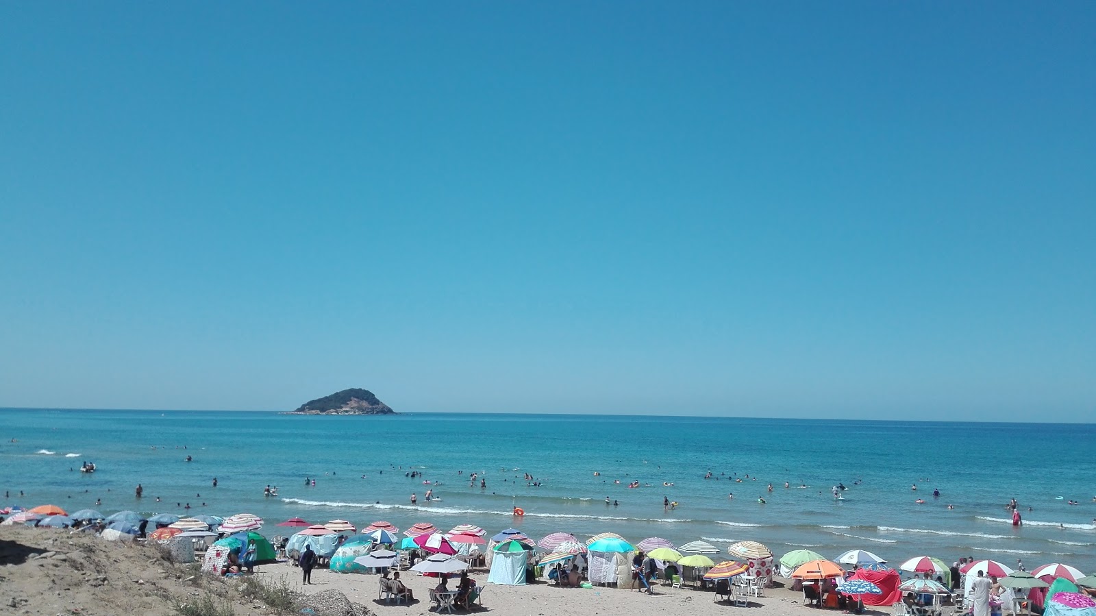 Foto di Awana Beach con una superficie del sabbia beige e rocce
