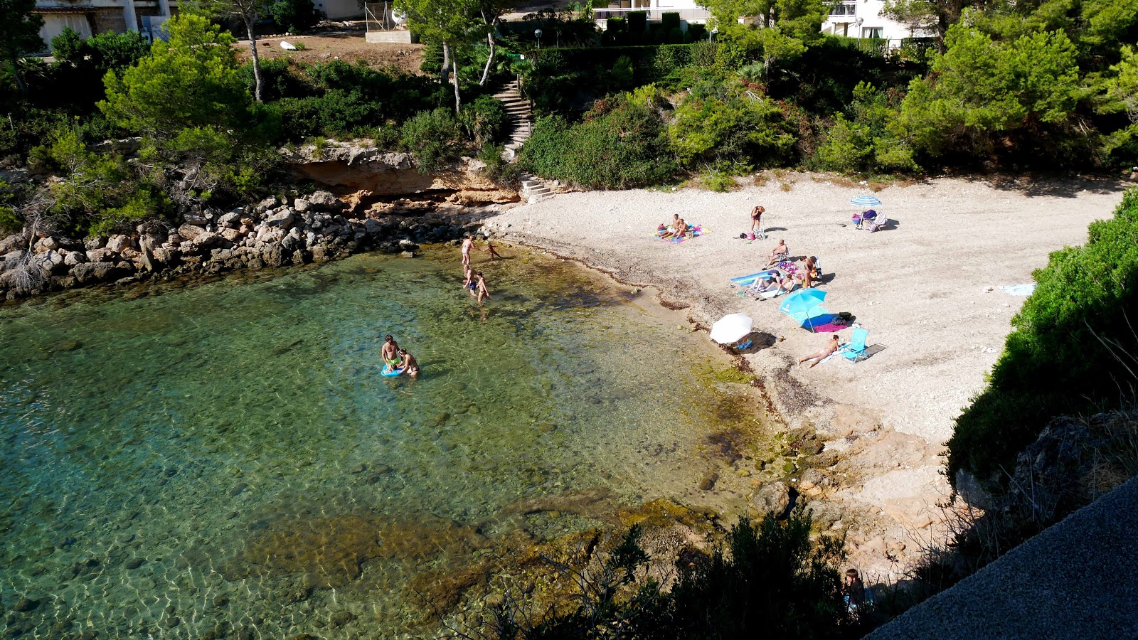 Photo de Cala Llobeta avec sable brun avec roches de surface