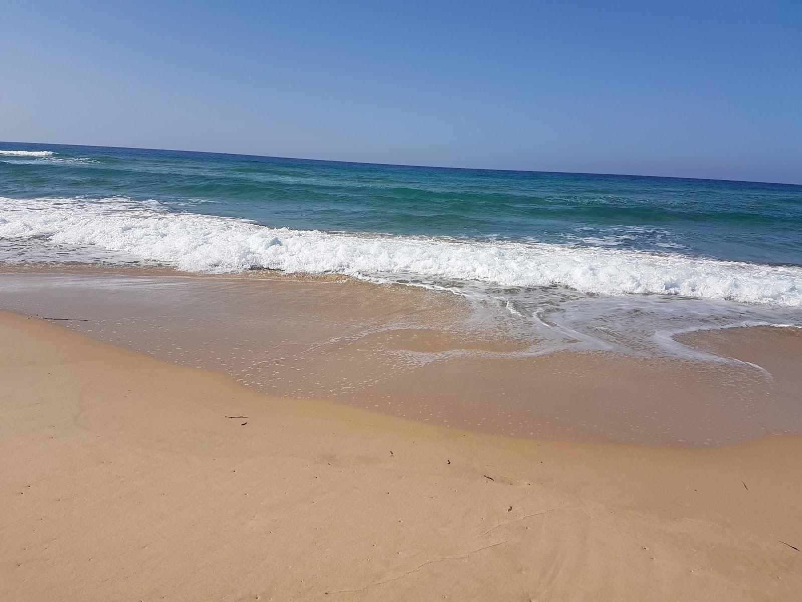 Foto av Plage Ain Damous omgiven av berg
