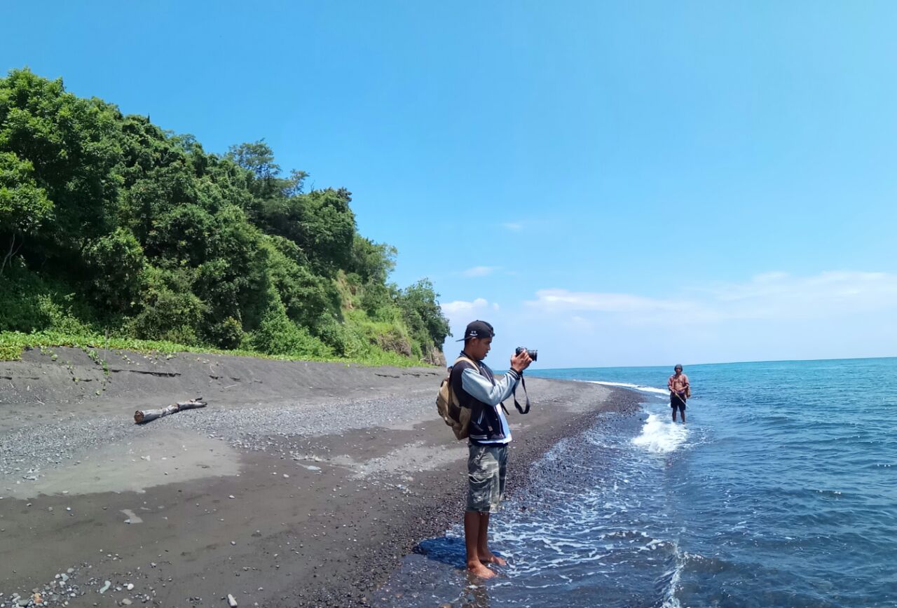 Foto di KesambiQ Beach con una superficie del sabbia marrone