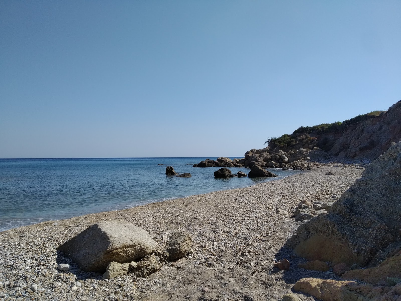 Foto von Nealia beach von Klippen umgeben